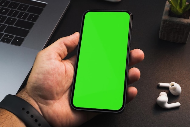 Man holding a smartphone with green screen on black background table Office environment Chroma Key