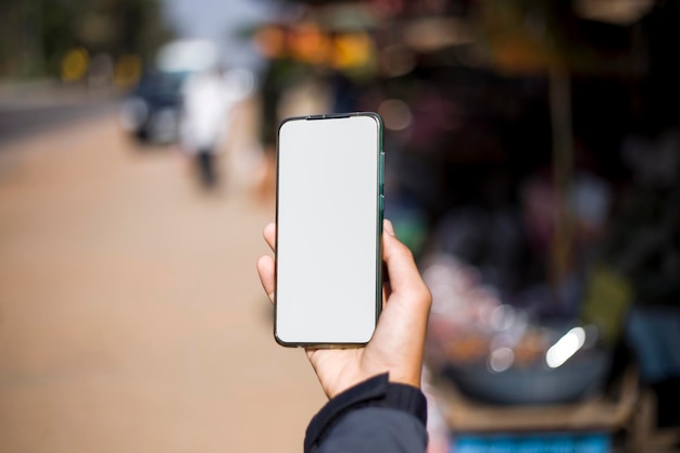 Un uomo che tiene in mano uno smartphone con uno schermo bianco per la creatività è un concetto.