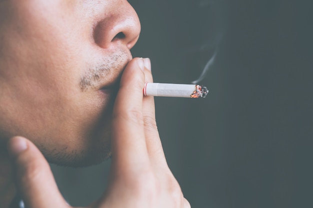 Foto uomo che tiene in mano il fumo di una sigaretta.