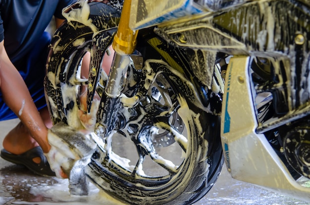 Man holding a sponge to wash the wheels motorcycle