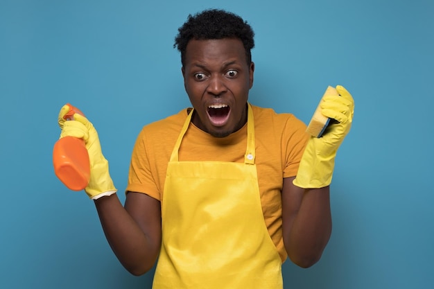 Photo man holding sponges and washing spray being upset not wanting to do cleaning