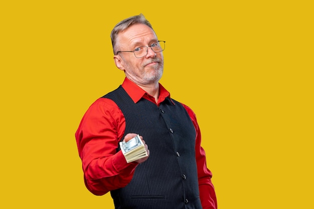 Man holding a stack of money in a red shirt and black vest A man in a red shirt and black vest holding a stack of money