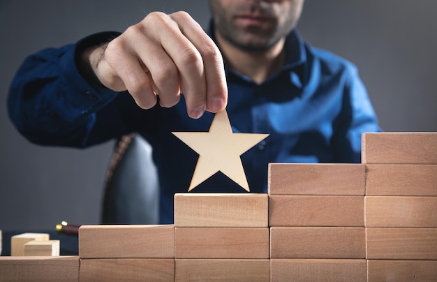 Man holding star on wooden block. Increase rating