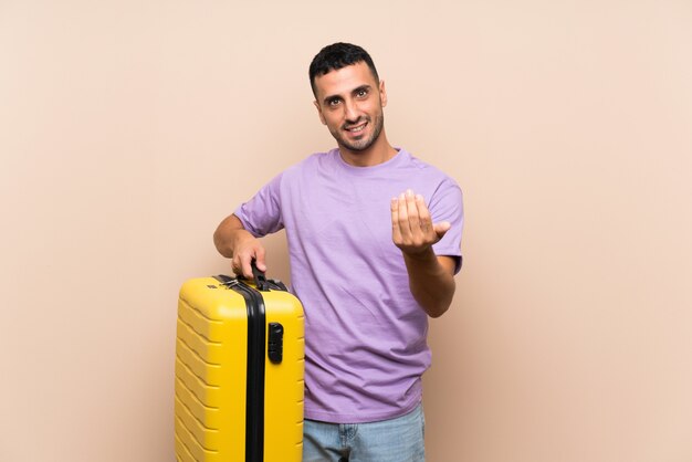 Man holding a suitcase inviting to come with hand. Happy that you came