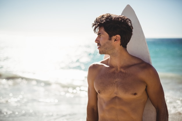 Man holding surfboard on beach