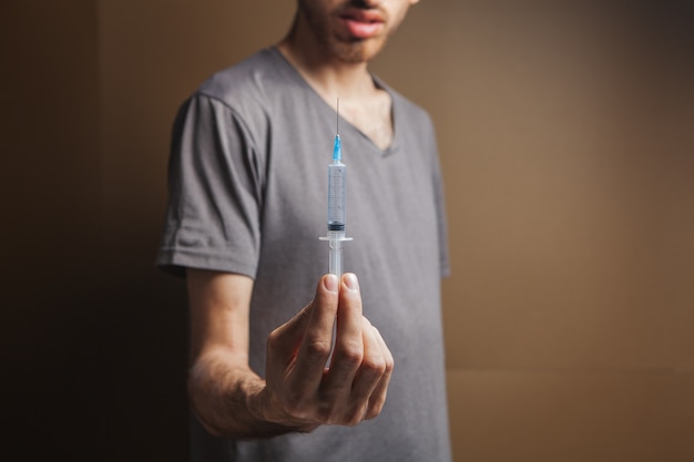 Man holding a syringe. addiction concept on brown background