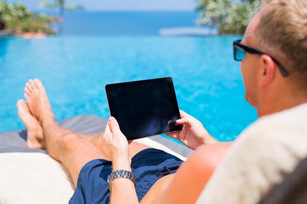 Man holding tablet in hands while on vacation in resort