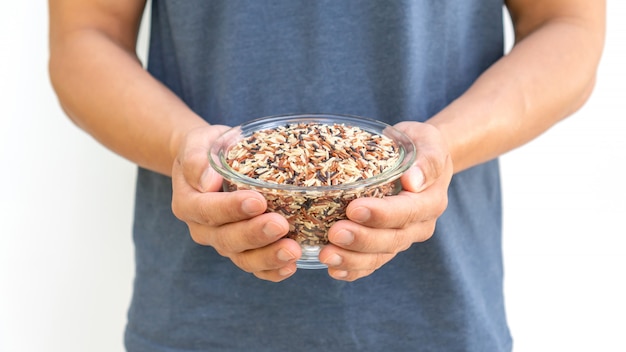 Man holding three colors (red, black, and brown) rice.