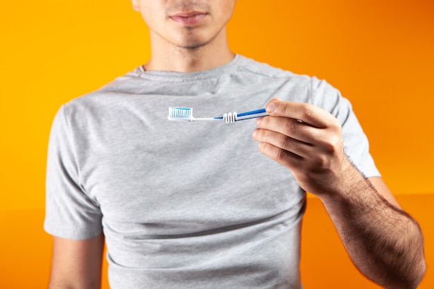 Man holding a toothbrush on an orange background