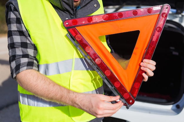 Un uomo che tiene un segno triangolare di un incidente