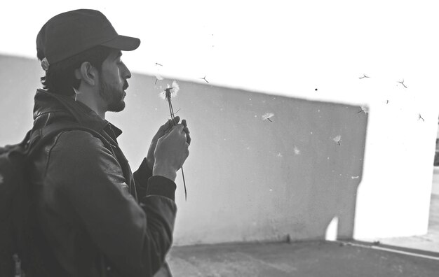 Man holding umbrella standing against sky