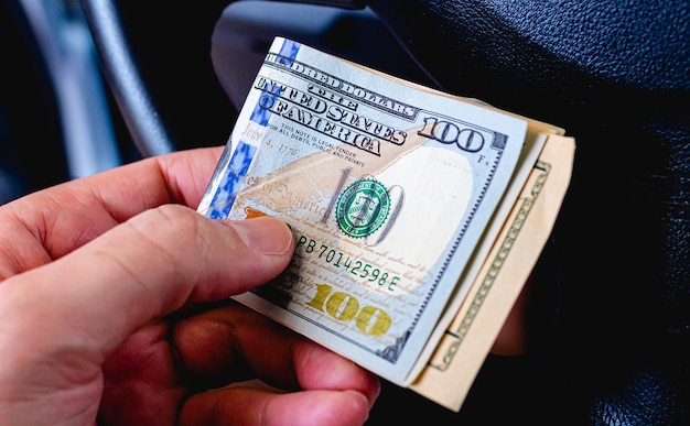 100달러 지폐가 강조 표시된 손에 미국 달러 지폐를 들고 있는 남자