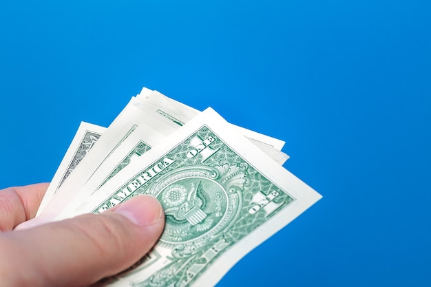 a man holding a wad us dollar bills with blue background 