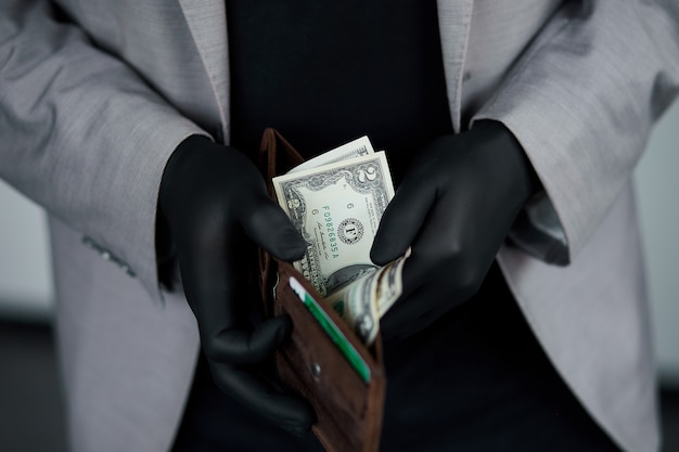 Man holding a wallet with  money dollars  in hand in black medical gloves. Save money. No money.  The world crisis