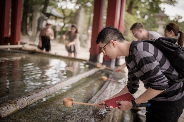 Photo man holding water in ladle at temple