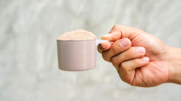 Man holding a whey protein on gray background.