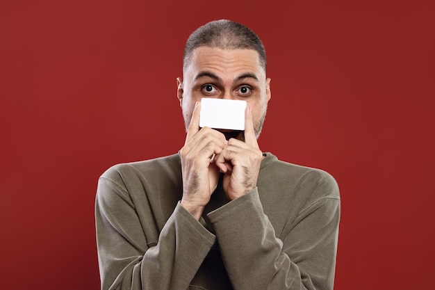 Man holding a white card with both hands and covering his nose