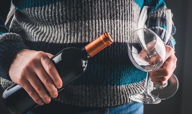 Man holding wine bottle and glasses closeup on black background guy with grape alcohol beverage and