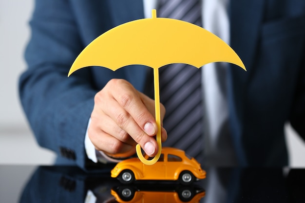 Photo man holding wood umbrella above car