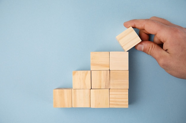 Man holding wooden cubes on the blue table