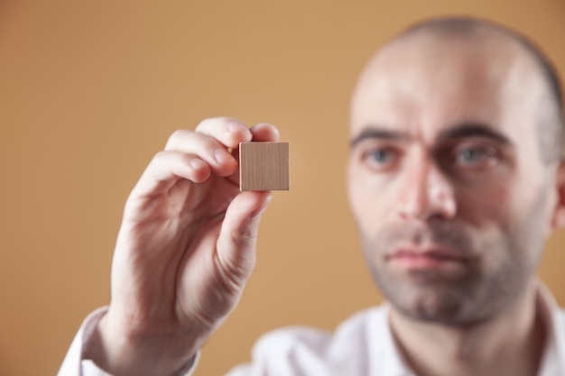 Man holding wooden empty cube.