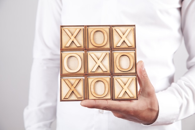 Man holding wooden X, O game.