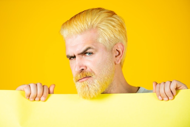 Uomo che tiene un cartellone bianco giallo isolato su sfondo colorato