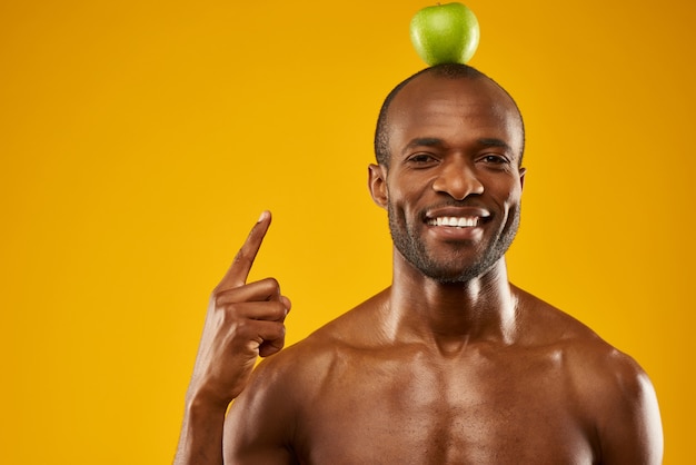 男は頭の上にリンゴを保持します。グリーンワールドのコンセプトです。