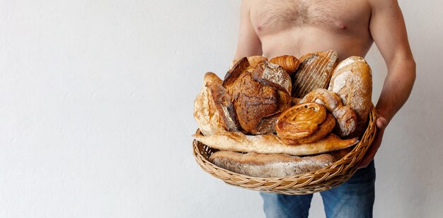 A man holds a basket of fresh pastries Bread rolls loaf croissants