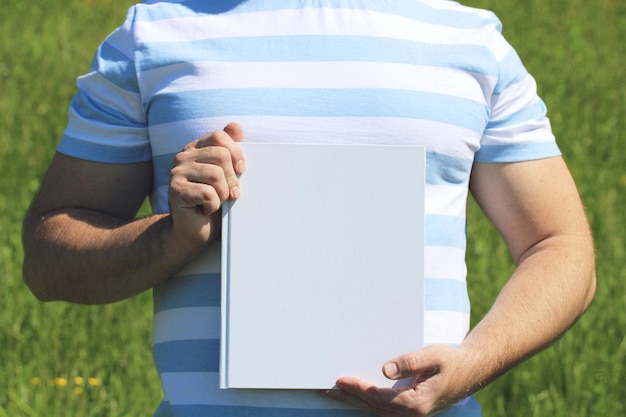 A man holds a book with an empty cover Mockup place to mount your object