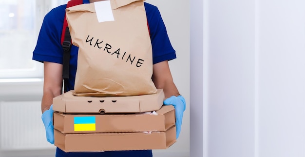 한 남자가 우크라이나와 러시아 간의 전쟁에서 자신을 찾은 우크라이나 난민과 가난한 시민들을 위한 구호품 상자를 들고 있습니다. 인도적 지원 개념 난민을 위한 기부
