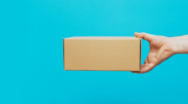 A man holds boxes in his hands on a blue background. Service delivery of goods. City delivery service.