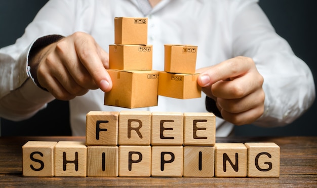 Photo a man holds boxes over the inscription free shipping. transportation of goods and services