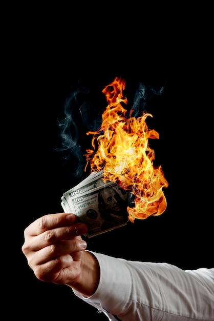 Man holds burning money in his hand