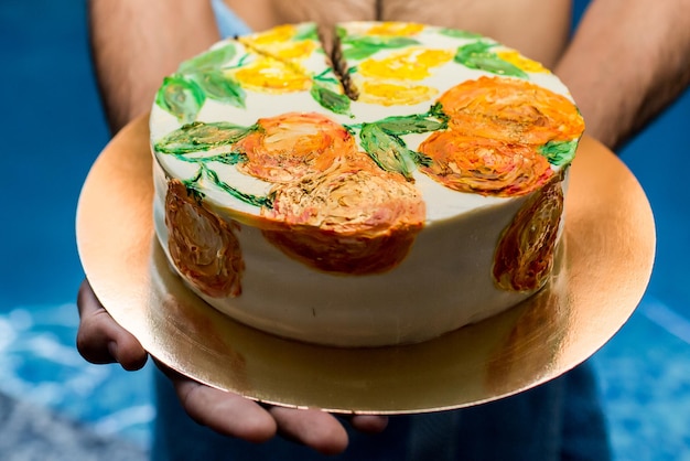 L'uomo tiene una torta decorata con arance e limoni dipinti. concetto di compleanno.