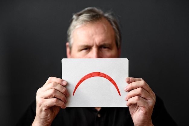 Photo man holds a card with sad emotions in front of his face