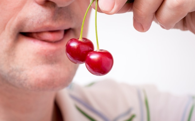 Photo a man holds cherries in his hand and wants to eat it. seductive cherries_