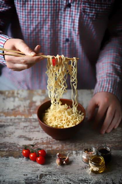 A man holds chopsticks with chinese noodles.