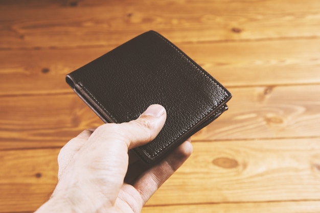 Man holds closed leather wallet in hand