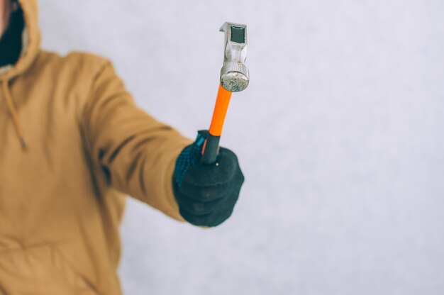 A man holds a construction hammer in his hands on a light.