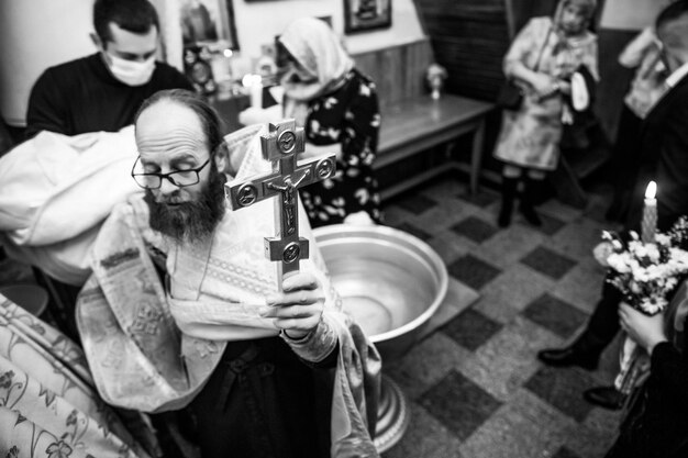 A man holds a cross in a church.