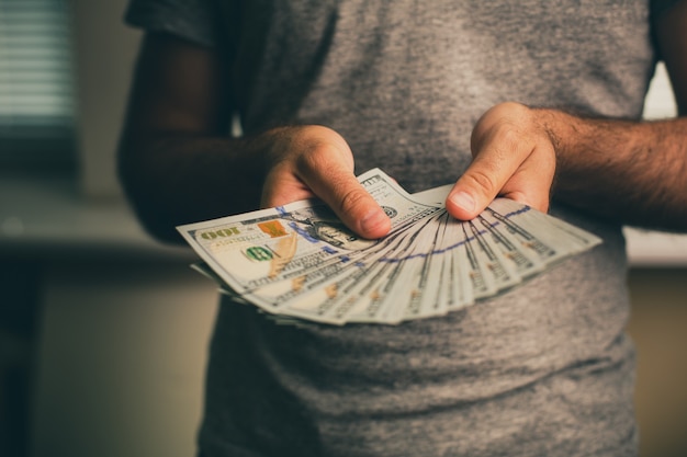 Photo a man holds dollars in his hands