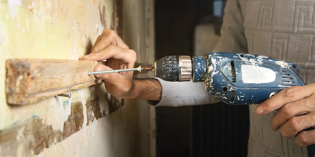 L'uomo tiene un trapano facendo lavori di ristrutturazione domestica