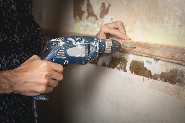 Man holds a drill. Doing home renovation