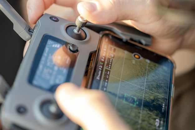 A man holds a drone remote control in his hands controlling the drone from a distance