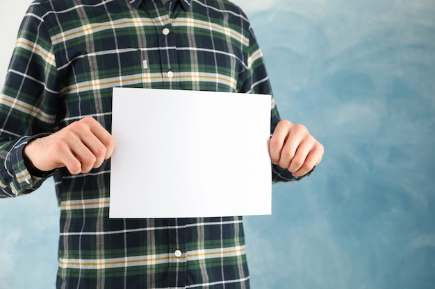 Photo man holds empty sheet on blue surface