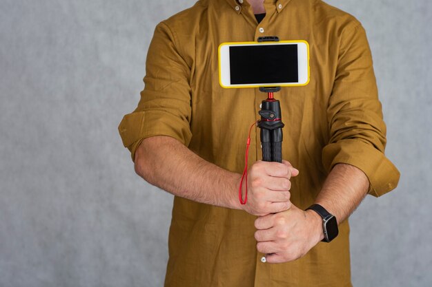 A man holds a flexible tripod with a mock-up of a smartphone with a black screen.