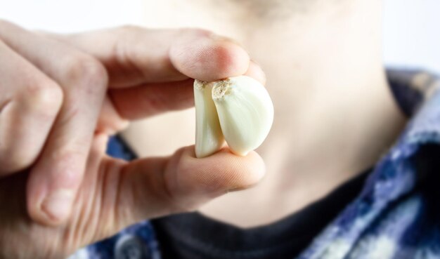 Foto un uomo tiene l'aglio in mano aglio naturale in mano closeupa spicchio d'aglio