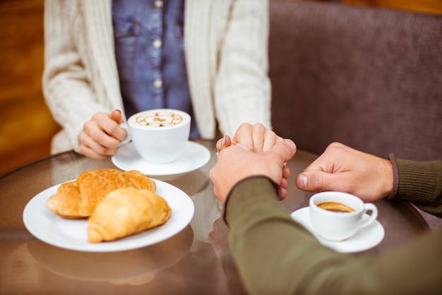 A man holds a girl's hand in a cafe.