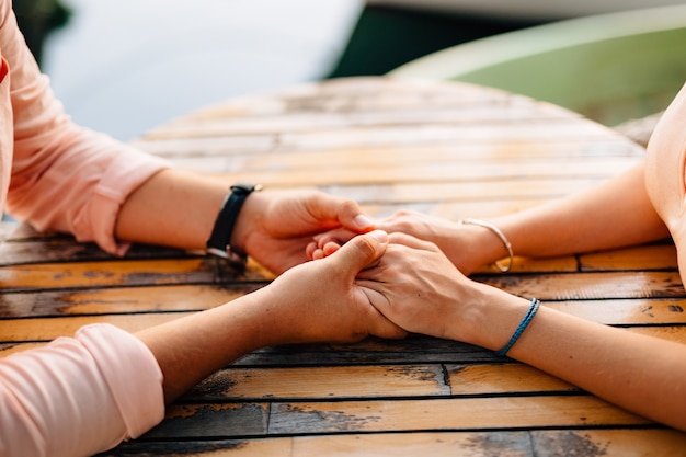 Man holds girls hands on a wooden table closeup